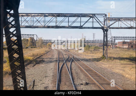 Vorderansicht eines Hell sonnendurchfluteten Bahnhof Hof und Titel mit Laub aus einem Zug Auto oder Lokomotive Stockfoto