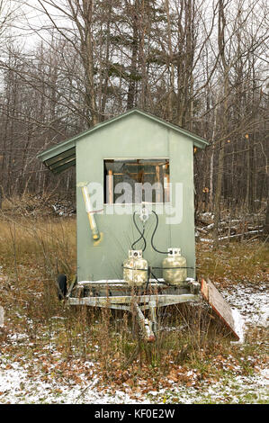 Kleine Hirsche blind mit Gasflaschen auf einem Anhänger im verschneiten Wald mit Blattlosen Laubbäume Jäger während der rotwildjagd zu verbergen Stockfoto