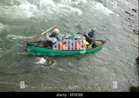 Zwei Männer navigieren eine überladene Kanu durch Stromschnellen während ein Abenteuer auf einem wilden Alaskan River. Stockfoto