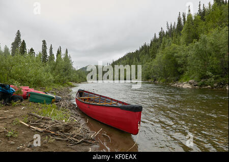 Eine auf Rot, aufblasbares Kanu auf einem alaskan River mit feuchten Gang und Ausrüstung trocknen am Flussufer. Stockfoto
