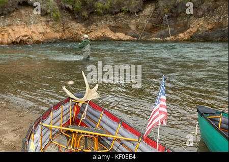 Zwei Kanus zog am Flussufer und mann Fliegenfischen im Hintergrund auf einem wilden Alaskan River. Stockfoto