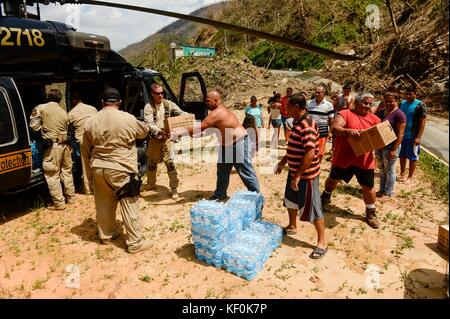 US-Zoll- und Grenzschutzbeamte und örtliche Freiwillige entladen während der Hilfsmaßnahmen nach dem Hurrikan Maria 11. Oktober 2017 in der Nähe von Utuado, Puerto Rico, Wasser und Notvorräte aus einem UH-60L Black Hawk Hubschrauber. Stockfoto