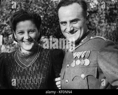 Dieses Bild zeigt einen Mann und eine Frau, beide mit einer Medaille, die möglicherweise eine Auszeichnung oder Anerkennung widerspiegelt. Das Foto nimmt wahrscheinlich einen historischen Moment mit einer öffentlichen oder zeremoniellen Veranstaltung auf. Stockfoto