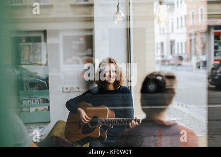 Portrait der junge blonde Sängerin Zupfen einer Gitarre Stockfoto