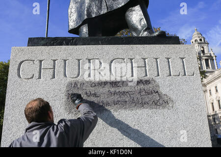 London, Großbritannien. 25 Okt, 2017 westminster Rat anti Graffiti Einheit waschen und die Graffiti mit dem Schreiben noch lesbar'' Gefängnis und nazistischen Lager sauber sind, die gleiche Sache' auf die Statue von Sir Winston Churchill gegenüber dem Palast von Westminster von Calais Dschungel Demonstranten nach links , um die vorherige Tag. Credit: Amer ghazzal/alamy leben Nachrichten Stockfoto