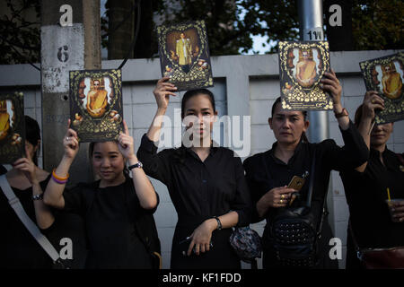 Bangkok, Thailand. Oktober 2017. Die Trauernden halten mehrere Porträts von König Rama 9, während sie sich anstellen, um Thailands Begräbniszeremonie und Einäscherung in Sanam Luang vor dem Großen Palast zu besuchen. Am ersten Tag wird die Königliche Urne zum Königlichen Krematorium für die eigentliche Einäscherung gebracht, und seine königlichen Reliquien und Asche werden an den folgenden Tagen zurück zum Großen Palast und in zwei verschiedene Tempel in Bangkok gebracht. Guillaume Payen/SOPA/ZUMA Wire/Alamy Live News Stockfoto