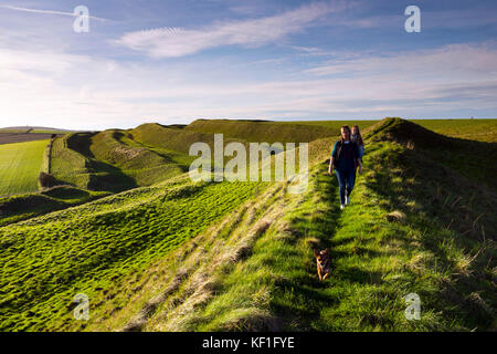 Maiden Castle, Dorchester, Großbritannien. 25. Oktober 2017. UK Wetter. Hund Wanderer genießen Sie am späten Nachmittag im Herbst Sonnenschein an Maiden Castle Eisenzeit Hill Fort in der Nähe von Dorchester, Dorset. Photo Credit: Graham Jagd-/Alamy leben Nachrichten Stockfoto