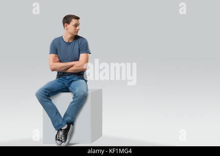 Mann sitzt auf einem Würfel und Wegsehen - isoliert. Platz für Text Stockfoto