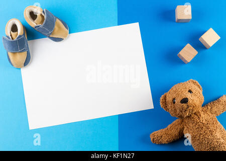 Sein ein Junge, blau Thema Baby Dusche oder Baumschule Hintergrund mit leere Karte, Teddy besr, Holzblöcke und Baby Schuhe Stockfoto