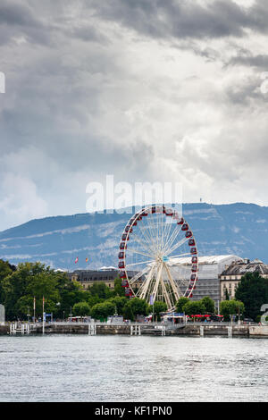 Blick auf die Rhône und die Altstadt mit dem Riesenrad und einem Park am Ufer unter einem bewölkten Himmel. Genf, Schweiz. Stockfoto