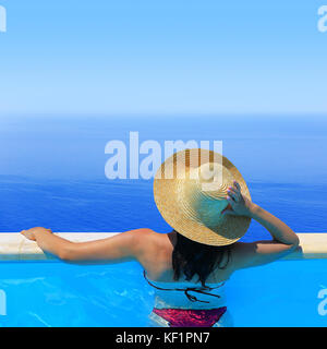 Frau in hat mit Blick auf die Seenlandschaft von der Poolbar Stockfoto