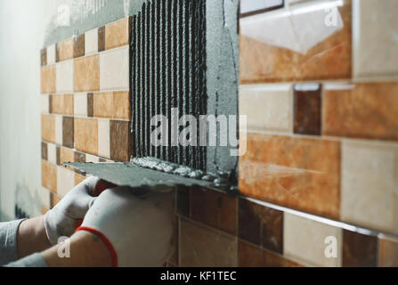 Festlegung der Keramikfliesen. fliesenleger Angebote fliesenkleber an der Wand Stockfoto