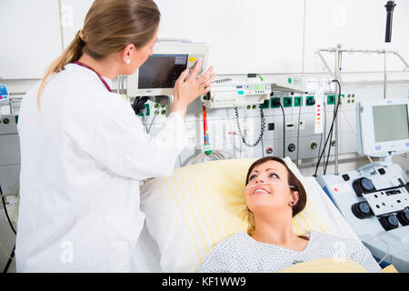 Arzt in der intensiven medizinischen Versorgung überprüfen der Resultate von Frau patie Stockfoto