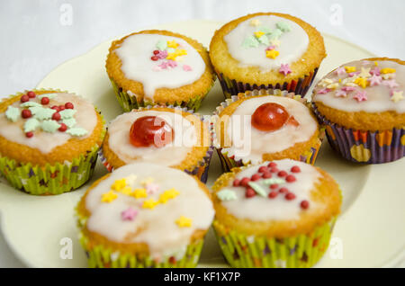 Eine Nahaufnahme eines hausgemachten Cupcakes mit Zuckerglasur, Gletscher Kirschen und Streuseln. Stockfoto