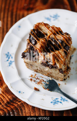 Brotpudding mit Karamell Sauce serviert mit einer Tasse heißen Kakao auf dunklen rustikalen Hintergrund Stockfoto