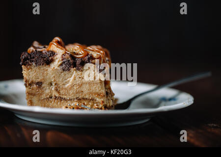 Brotpudding mit Karamell Sauce serviert mit einer Tasse heißen Kakao auf dunklen rustikalen Hintergrund Stockfoto