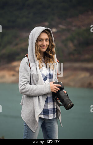 Blonde Frau Fotograf in Jeans, kariertes Hemd und Grauer Hoodie mit langen Brennweiten Stockfoto