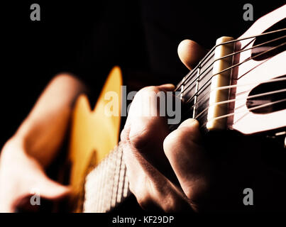 Flamenco-Gitarrist aus der Nähe, spielen traditionelle akustische Gitarre Konzept Bild uns als Hintergrund, hoher Kontrast, selektive Fokus auf Vordergrundfing Stockfoto