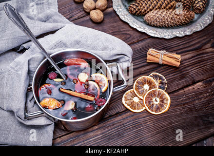 In einem Stahl gekocht pan Glühwein mit Gewürzen und Früchten auf einem braunen Holz- Hintergrund, Ansicht von oben Stockfoto