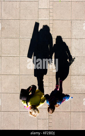 Schatten einer Mutter und Tochter gehen Hand in Hand, die auf Stadt Bürgersteig von oben Stockfoto