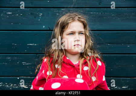 Mädchen mit Bademantel im Freien an Holzhütte sitzen Stockfoto