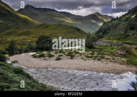 Die steinbogenbrücke an der Seite des dramatischen a87 Mountain Pass durch kintail in Richtung Kyle von lochalsh in der westlichen schottischen Highlands Stockfoto