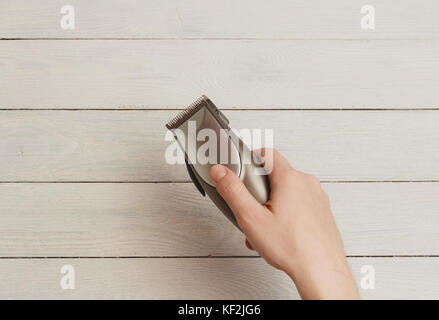 Mann hand Haarschneidemaschinen auf weißem Holz- Hintergrund Stockfoto