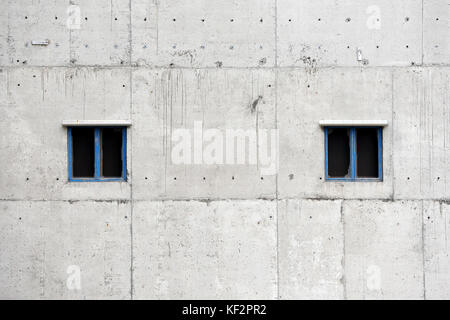 Zwei symmetrische angrenzenden geteilte Fenster mit blauen Fensterrahmen auf grauen Betongebäude in Alte Werft Dorf siglufjordur, Island Stockfoto