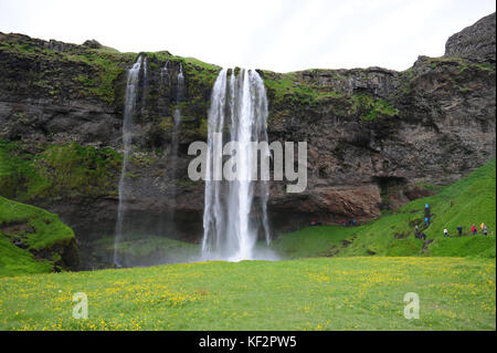 Viele Touristen entlang Pfad neben und hinter dem Wasserfall Seljalandsfoss touristische Destination South Iceland Stockfoto