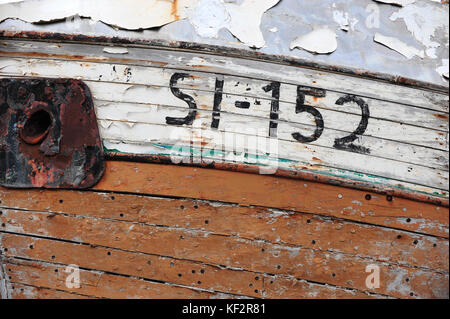 Geschälte Farbe auf verwitterte rosten Holzrumpf Boards an der Seite des Boot Schiff mit Nummern und Buchstaben in siglufjordur Werft, North Island Stockfoto