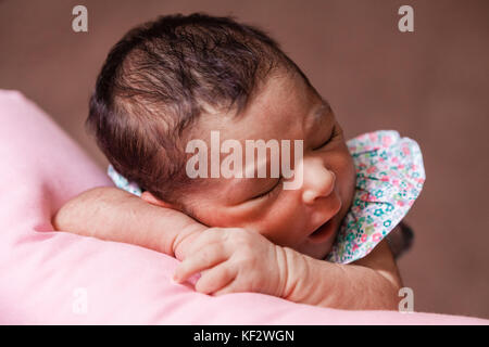 Nahaufnahme, Porträt einer niedlichen Zwei Wochen alte Neugeborene Mädchen mit einem geblümten Kleid, schlief friedlich über ein Kissen/Neugeborenen baby portrait cute Stockfoto