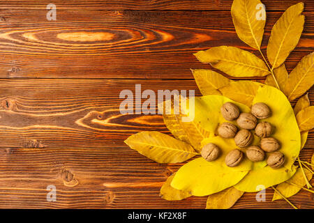 Walnüsse mit Herbst gelb Nussbaum Blätter vor dem Hintergrund einer alten Holztisch. Stockfoto