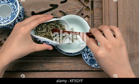 Eine braune Teekanne durch einen Trichter füllen. Porzellan-Tassen, Stahl-Teelöffel. Schwarz, grün, puerh, Oolong, tieguanyin, sencha, Tee Stockfoto