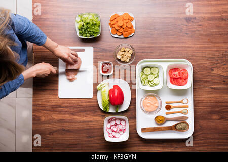 Hohe Betrachtungswinkel von Frau Schneiden von rohem Fleisch auf Schneidebrett, beim Kochen in der Küche Stockfoto