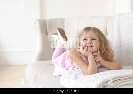 Charmantes kleines Mädchen posiert auf dem Sofa auf einem weißen Hintergrund Stockfoto