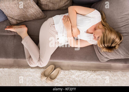 Hochwinkelansicht Einer Jungen Frau Mit Magenschmerzen Auf Dem Sofa Zu Hause Stockfoto
