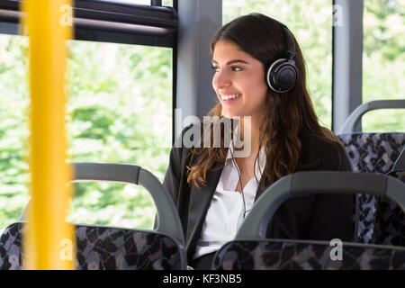 Happy geschäftsfrau Musik hören beim Reisen mit dem Bus Stockfoto