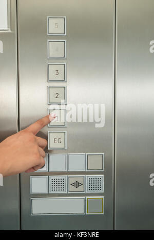 Nahaufnahme der weiblichen Hand drücken der Taste in der ersten Etage Aufzug Stockfoto
