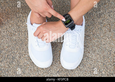 Erhöhte Ansicht einer weiblichen Athleten in den weißen Schuhen Berühren bei Smart Watch Stockfoto