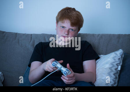 Junge auf dem Sofa zu Hause spielt Videospiele sitzen Stockfoto