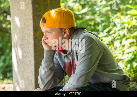 Verärgert Junge sitzt im Park mit der Hand auf den Kopf Stockfoto