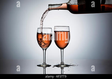 Gießen Rose' Wein bilden eine Flasche Wein in die Gläser. Stockfoto