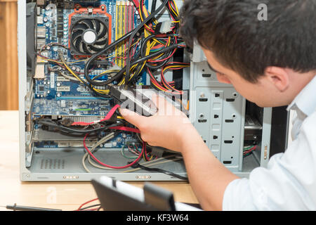 Ein junger Techniker arbeiten an defekten Computer in seinem Büro Stockfoto