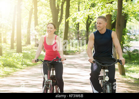 Junge glückliches Paar Fahrrad im Park Stockfoto