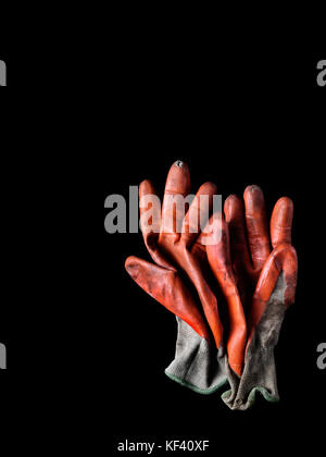 Dreckig abgenutzt orange Gummi beschichtete Arbeitshandschuhe auf Schwarz Stockfoto