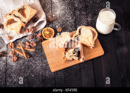 Köstliche Mahlzeit Bild von oben mit Pound Cake, Mandeln, Walnüsse und eine Tasse Milch, auf einem schwarzen Holztisch Stockfoto