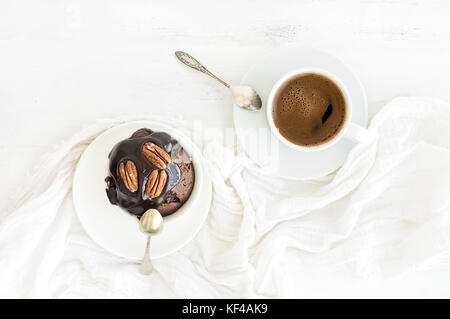 Leckere hausgemachte brown Muffin mit Ganache Vereisung und Pekannuss, Tasse schwarzen Kaffee. Stockfoto