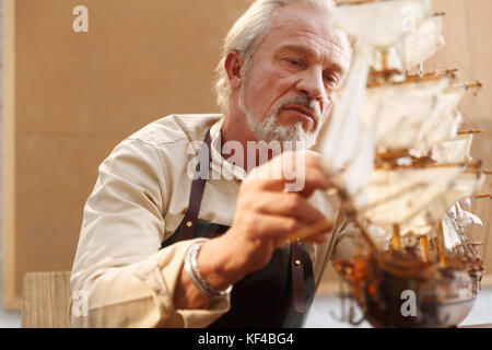 Der alte Mann ist ein Segelboot Modell Stockfoto