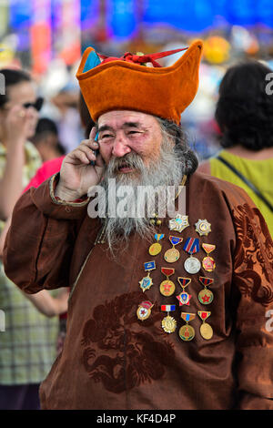 Älterer Mann mit Bart, Kopf - Kleid und Medaillen spricht auf ein Mobiltelefon, Ulaanbaatar, Mongolei Stockfoto