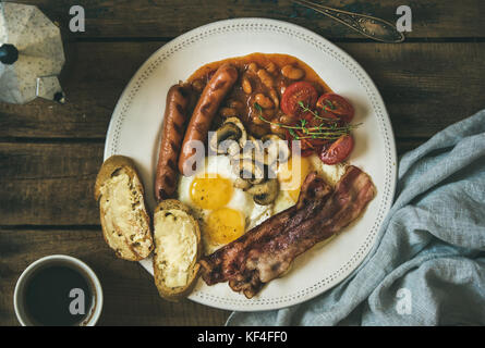 Englisches Frühstück mit Spiegelei, Würstchen, Pilze, Speck, Bohnen, Kaffee Stockfoto